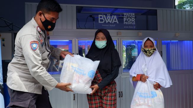 Petugas polisi memberikan bantuan kepada warga Kampung Gobah dari Program Wakaf Sarana Air Bersih. [dokumentasi pribadi]