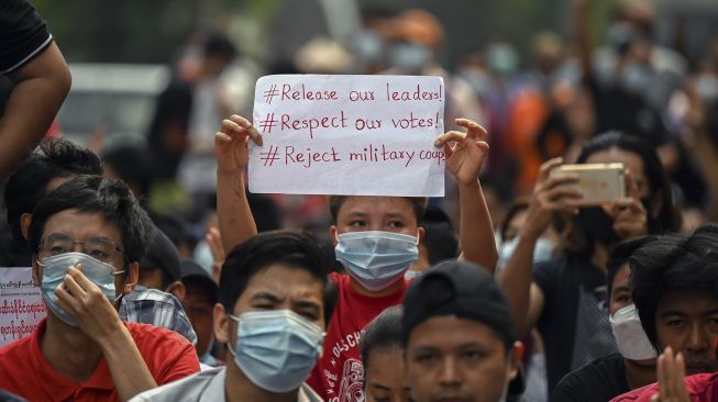 Seorang pengunjuk rasa muda memegang poster selama demonstrasi menentang kudeta militer di Yangon, Myanmar, Sabtu (6/2/2021). [YE AUNG THU / AFP]