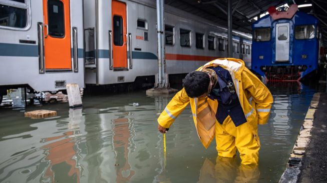 Karyawan mengukur ketinggian banjir pada lintasan kereta api di Stasiun Tawang, Semarang, Jawa Tengah, Sabtu (6/2/2021). [ANTARA FOTO/Aji Styawan]
