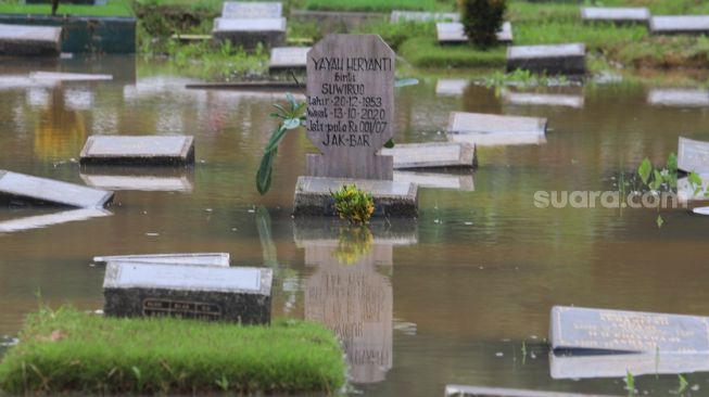 Penampakan salah satu makam yang terendam banjir di TPU Karet Bivak, Jakarta Pusat, Minggu (7/2/2021). [Suara.com/Alfian Winanto]