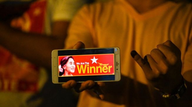 Seorang pendukung partai Liga Nasional untuk Demokrasi (NLD) memegang ponsel yang menunjukkan gambar Aung San Suu Kyi di depan markas partai di Yangon. Militer Myanmar menahan Penasihat Negara Aung San Suu Kyi dan Presiden Win Myint di Naypyitaw, terkait kisruh politik nasional terutama setelah pelaksanaan pemilihan umum yang dimenangi Partai Liga Nasional untuk Demokrasi (NLD) pimpinan Aung San Suu Kyi. [Foto/AFP]