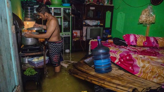 Seorang warga memasak di dalam rumahnya yang terendam banjir di Kelurahan Tanjung Mas, Semarang, Jawa Tengah, Sabtu (6/2/2021). [ANTARA FOTO/Aji Styawan]