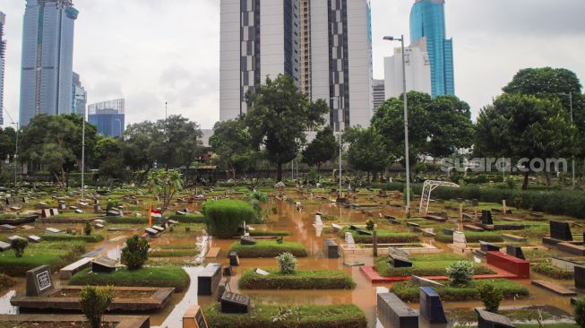 Suasana di area pemakaman yang terendam banjir di TPU Karet Bivak, Jakarta Pusat, Minggu (7/2/2021). [Suara.com/Alfian Winanto]