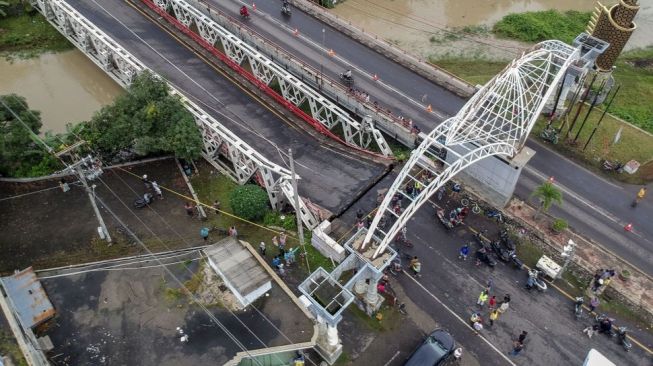 Foto udara jembatan perbatasan yang ambles di Kabupaten Pekalongan, Jawa Tengah, Jumat (5/2/2021). Jembatan perbatasan antara Kabupaten Pekalongan dan Kabupaten Pemalang bagian sisi selatan yang dibangun pada 1977 itu ambles pada Kamis (4/2) malam sedalam sekitar dua meter. ANTARA FOTO/Harviyan Perdana Putra