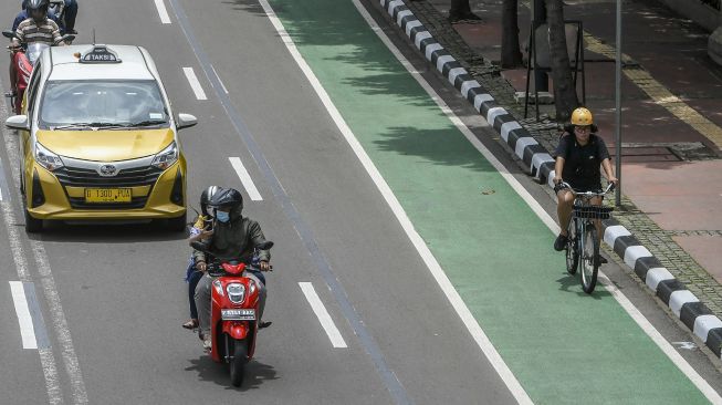 Pesepeda melintasi jalur sepeda di Jalan MH Thamrin, Jakarta, Sabtu (6/2/2021). ANTARA FOTO/Galih Pradipta
