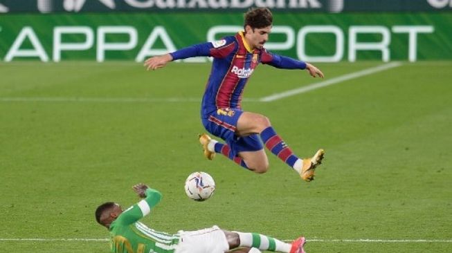 Pemain Barcelona Francisco Trincao menghindari tekel pemain Real Betis dalam pertandingan La Liga yang berlangsung di Estadio Benito Villamarin, Senin (8/1/2021). [AFP]