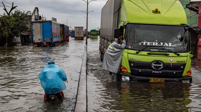 Sejumlah truk menembus jalur Pantura Jalan Raya Kaligawe - Genuk yang terendam banjir di Genuk, Semarang, Jawa Tengah, Senin (8/2/2021). [ANTARA FOTO/Aji Styawan]
