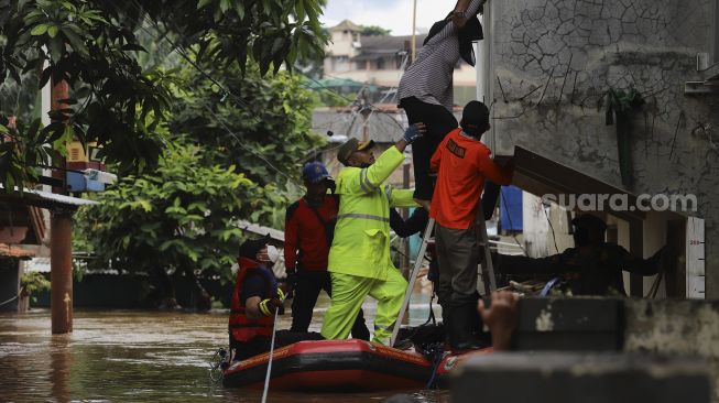 Petugas Pemadam Kebakaran bersama petugas Satpol PP menggunakan perahu karet mengevakuasi warga yang terjebak banjir di rumahnya di kawasan Pejaten Timur, Pasar Minggu, Jakarta, Senin (8/2/2021). [Suara.com/Angga Budhiyanto]