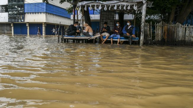 Warga terjebak banjir di Jalan Jatinegara Barat, Kampung Pulo, Jakarta, Senin (8/2/2021). [ANTARA FOTO]