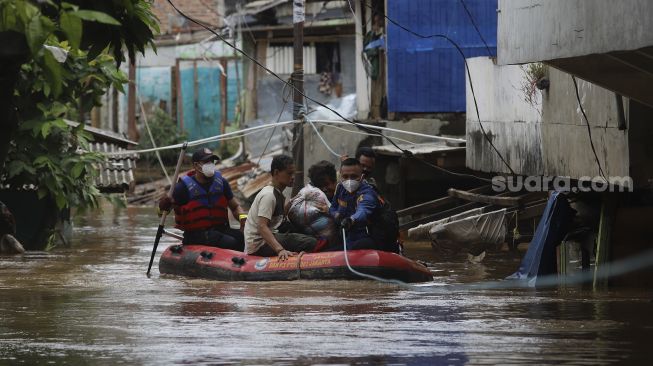 Petugas Pemadam Kebakaran menggunakan perahu karet mengevakuasi warga yang terjebak banjir di rumahnya di kawasan Pejaten Timur, Pasar Minggu, Jakarta, Senin (8/2/2021). [Suara.com/Angga Budhiyanto]