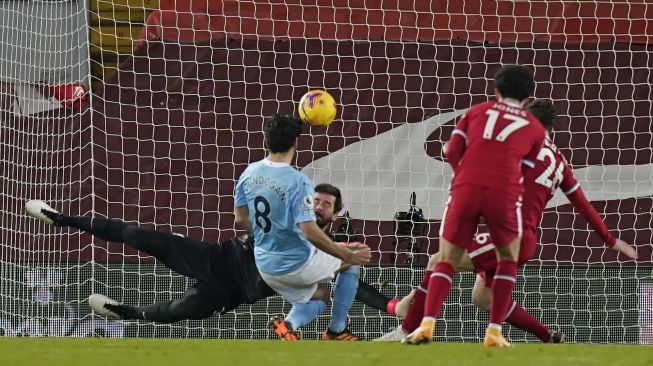 Kiper Liverpool Alisson Becker mencoba menahan tendangan dari gelandang Manchester City Ilkay Gundogan selama pertandingan sepak bola Liga Inggris antara Liverpool melawan Manchester City stadion Anfield, Liverpool, Inggris, Senin (8/2/2021) dini hari WIB. Laurence Griffiths / POOL / AFP