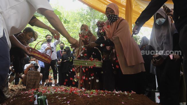 Kerabat dan keluarga menaburkan bunga ke pusara Ustadz Maaher At-Thuwailibi di Kompleks Pemakaman Pondok Pesantren Daarul Quran, Cipondoh, Tangerang, Banten, Selasa (9/2/2021). [Suara.com/Angga Budhiyanto]