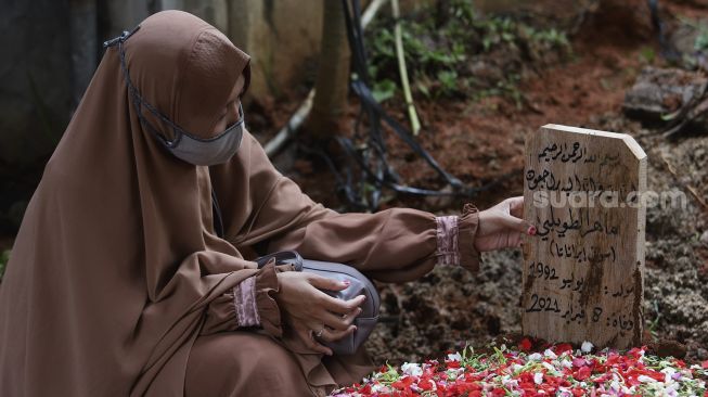 Istri dari Ustadz Maaher At-Thuwailibi, Iqlima Ayu berada di samping pusara suaminya usai prosesi pemakaman di Kompleks Pemakaman Pondok Pesantren Daarul Quran, Cipondoh, Tangerang, Banten, Selasa (9/2/2021). [Suara.com/Angga Budhiyanto]