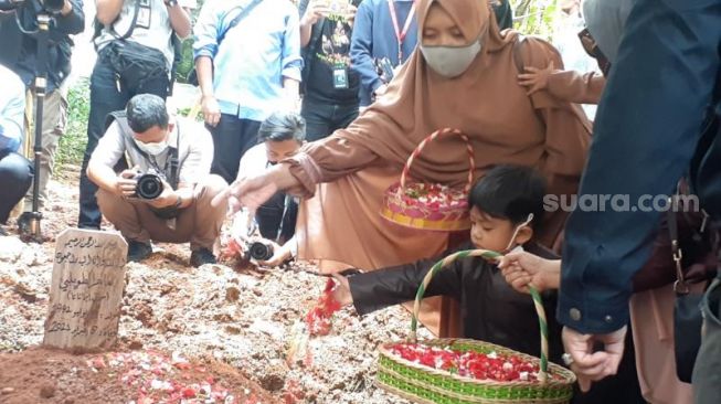 Salah satu balita putra Ustadz Maaher At-Thuwailibi ikut menabur bunga di pusara ayahnya usai dimakamkan di Pesantren Tahfiz Daarul Quran, Cipondoh, Kota Tangerang, Selasa (9/2/2021). [Suara.com/Wivy]