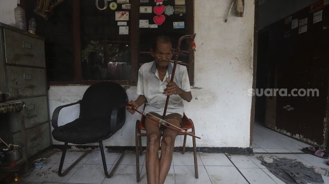 Pembuat alat musik Tehyan, Ghohyong memainkan alat musik buatannya di Kampung Tehyan, Kota Tangerang, Banten, Selasa (9/2/2021). [Suara.com/Angga Budhiyanto]