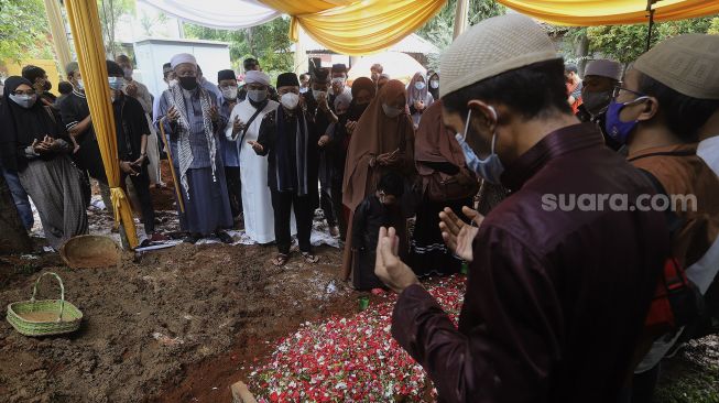 Kerabat dan keluarga memanjatkan doa di samping pusara Ustadz Maaher At-Thuwailibi di Kompleks Pemakaman Pondok Pesantren Daarul Quran, Cipondoh, Tangerang, Banten, Selasa (9/2/2021). [Suara.com/Angga Budhiyanto]