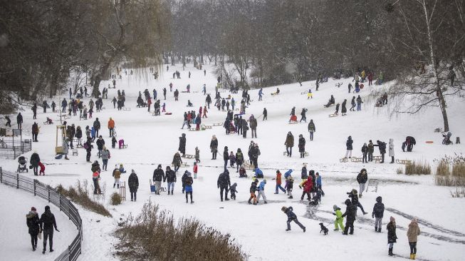 Sejumlah warga memanfaatkan salju untuk meluncur menggunakan kereta luncur mereka dan bermain di kolam beku di taman Wilmersdorf-Schoeneberg, distrik Schoeneberg, Berlin, pada (8/2/2021). [Odd ANDERSEN / AFP]