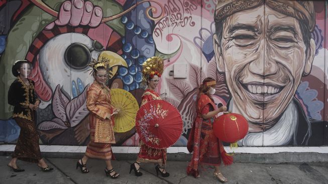 Warga yang mengenakan pakaian adat menyampaikan ucapan selamat Tahun Baru Imlek di jalan Gatot Subroto, Solo, Jawa Tengah, Rabu (10/2/2021). [ANTARA FOTO/Mohammad Ayudha]