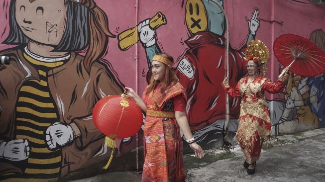 Warga yang mengenakan pakaian adat menyampaikan ucapan selamat Tahun Baru Imlek di jalan Gatot Subroto, Solo, Jawa Tengah, Rabu (10/2/2021). [ANTARA FOTO/Mohammad Ayudha]