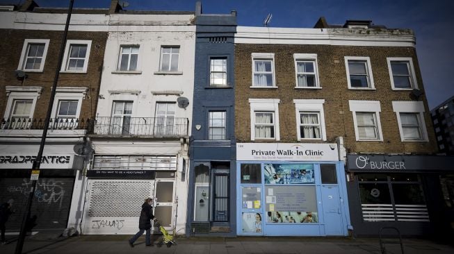 Seorang pejalan kaki melewati bagian depan 'rumah tertipis di London', London Barat, pada (5/2/2021). [Tolga Akmen / AFP]