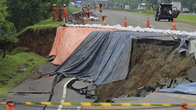 Pekerja memeriksa kondisi jalan tol yang ambles di ruas tol Cikopo-Palimanan (Cipali) KM 122, Kabupaten Subang, Jawa Barat, Rabu (10/2/2021). [ANTARA FOTO/Dedhez Anggara]