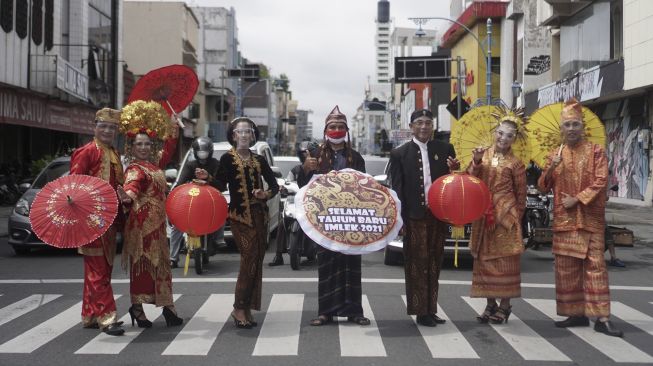 Warga yang mengenakan pakaian adat menyampaikan ucapan selamat Tahun Baru Imlek di jalan Gatot Subroto, Solo, Jawa Tengah, Rabu (10/2/2021). [ANTARA FOTO/Mohammad Ayudha]