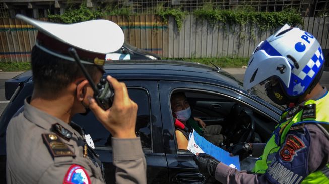 Petugas kepolisian memeriksa surat keterangan sehat dari pengendara yang keluar di Gerbang Tol Cileunyi, Kabupaten Bandung, Jawa Barat, Kamis (11/2/2021).  ANTARA FOTO/Raisan Al Farisi