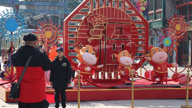 Warga Kota Beijing berfoto di depan dekorasi bertema Imlek di pusat jajanan kuno kawasan Qianmen pada hari pertama liburan Tahun Baru China di Beijing, China, Rabu (10/2/2021). ANTARA FOTO/M. Irfan Ilmie