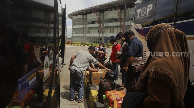 Sejumlah calon penumpang bersiap memasuki bus di Terminal Terpadu Pulo Gebang, Jakarta, Kamis (11/2/2021). [Suara.com/Angga Budhiyanto]