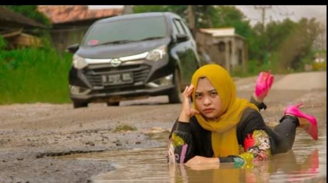 Wanita berpose di jalan rusak sebagai bentuk kritik pemerintah setempat (Facebook)