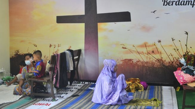 Pengungsi korban banjir berdoa usai melakukan shalat di ruang aula Gereja Kristen Muria Indonesia (GKMI) Tanjung Karang, Kudus, Jawa Tengah, Kamis (11/2/2021). [ANTARA FOTO/Yusuf Nugroho]