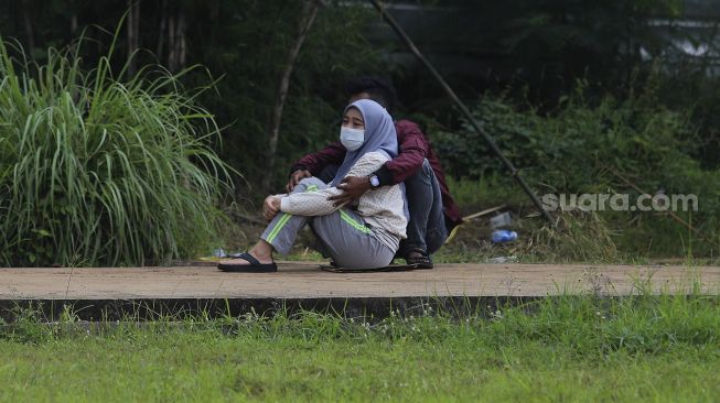 Keluarga menyaksikan dari kejauhan pemakaman jenazah korban COVID-19 di TPU Bambu Apus, Jakarta Timur, Sabtu (13/2/2021). [Suara.com/Angga Budhiyanto]