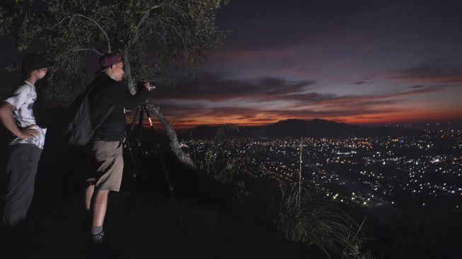 Sejumlah pengunjung memotret panorama kota dari Bukit Nobita di Kampung Jua, Padang, Sumatera Barat, Jumat (12/2/2021). [ANTARA FOTO/Iggoy el Fitra]