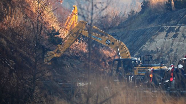 Gambar ini menunjukkan alat berat excavator listrik untuk pekerjaan restorasi di lokasi longsor di Joban Expressway di Soma, prefektur Fukushima pada 14 Februari 2021, setelah gempa bumi.  STR / JIJI PRESS / AFP
