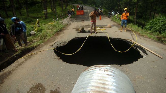 Sejumlah pekerja memperbaiki jalan yang berlubang di jalan provinsi penghubung Brebes dan Tegal, Desa Batursari, Sirampog, Brebes, Jawa Tengah, Minggu (14/2/2021). ANTARA FOTO/Oky Lukmansyah
