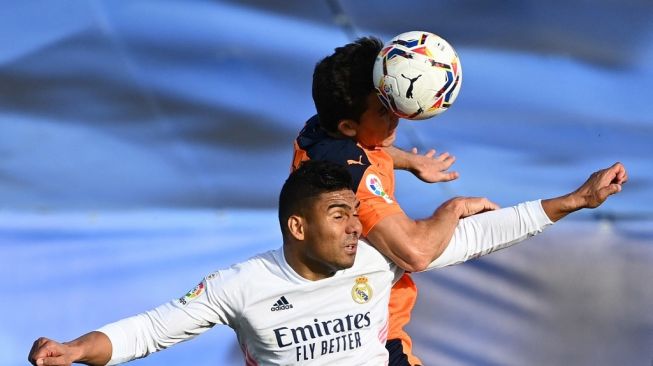 Bek Valencia, Gabriel Paulista (kanan) berebut bola dengan gelandang Real Madrid, Casemiro dalam laga pekan ke-23 Liga Spanyol di Stadion Alfredo Di Stefano, Valdebebas, Minggu (14/2/2021) malam WIB. [GABRIEL BOUYS / AFP].