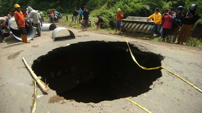 Sejumlah pekerja memperbaiki jalan yang berlubang di jalan provinsi penghubung Brebes dan Tegal, Desa Batursari, Sirampog, Brebes, Jawa Tengah, Minggu (14/2/2021). ANTARA FOTO/Oky Lukmansyah
