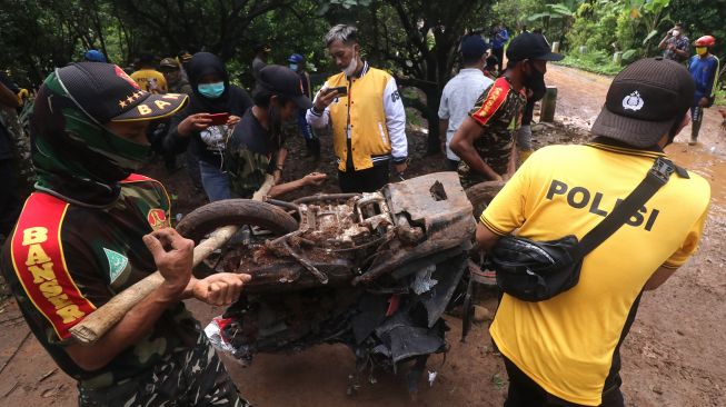 Polisi bersama relawan mengevakuasi sepeda motor di kawasan longsor Desa Ngetos, Nganjuk, Jawa Timur, Senin (15/2/2021). [ANTARA FOTO/Prasetia Fauzani]
