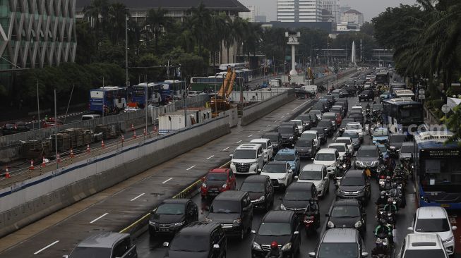 Sejumlah kendaraan melintas di samping pembangunan proyek MRT Fase II Bundaran HI-Harmoni di Jalan M.H Thamrin, Jakarta, Selasa (16/2/2021). [Suara.com/Angga Budhiyanto]