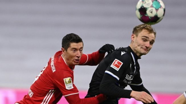 Penyerang Bayern Munich Robert Lewandowski (kiri) berduel dengan bek Arminia Bielefeld Amos Pieper (kanan) pada pertandingan Liga Jerman yang dimainkan di Allianz Arena, Munich, Senin (15/2/2021). (ANTARA/AFP/CHRISTOF STACHE)