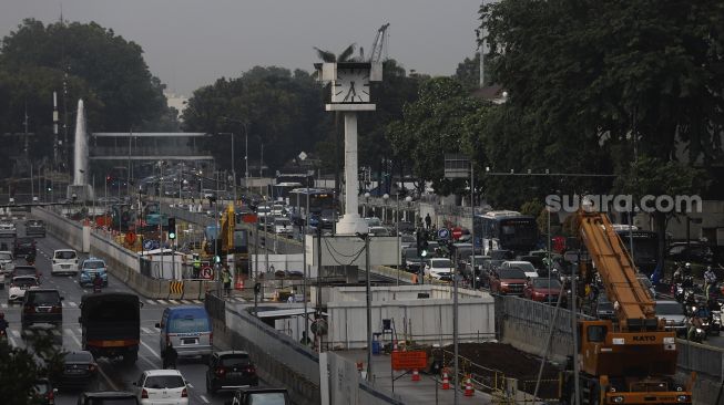 Sejumlah kendaraan melintas di samping pembangunan proyek MRT Fase II Bundaran HI-Harmoni di Jalan M.H Thamrin, Jakarta, Selasa (16/2/2021). [Suara.com/Angga Budhiyanto]