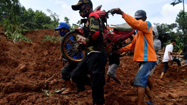 Warga mengevakuasi motor saat pencarian korban tanah longsor di Ngetos, Nganjuk, Jawa Timur, Senin (15/2/2021). ANTARA FOTO/Zabur Karuru