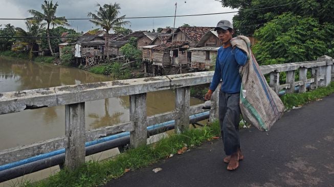 Pemulung melintas di Kampung Ciputri, Kasemen, Serang, Banten, Rabu (17/2/2021). [ANTARA FOTO/Asep Fathulrahman]