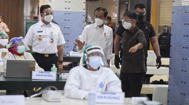 Presiden Joko Widodo (Jokowi) didampingi Menteri Kesehatan Budi Gunadi Sadikin (kanan) dan Gubernur DKI Jakarta Anies Baswedan meninjau vaksinasi COVID-19 massal bagi pedagang di Pasar Tanah Abang Blok A, Jakarta, Rabu (17/2/2021).  ANTARA FOTO/Hafidz Mubarak 