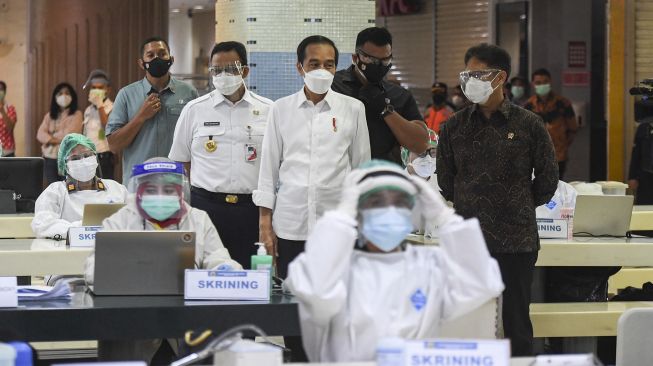 Presiden Joko Widodo (tengah) didampingi Menteri Kesehatan Budi Gunadi Sadikin (kanan) berbincang dengan Gubernur DKI Jakarta Anies Baswedan saat meninjau vaksinasi COVID-19 massal bagi pedagang di Pasar Tanah Abang Blok A, Jakarta, Rabu (17/2/2021). ANTARA FOTO/Hafidz Mubarak 