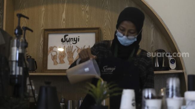 Barista yang seorang tunarungu meracik kopi pesanan pengunjung di Kafe Sunyi, Cilandak, Jakarta Selatan, Kamis (18/2/2021). [Suara.com/Angga Budhiyanto]