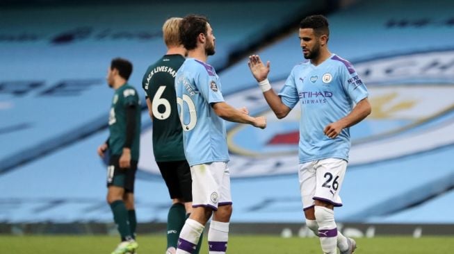 Gelandang Manchester City, Riyad Mahrez (kiri) dan Bernardo Silva melakukan selebrasi usai mencetak gol saat menghadapi Burnley dalam laga lanjutan Liga Inggris di Etihad Stadium, 22 Juni 2020. [Martin Rickett / POOL / AFP]