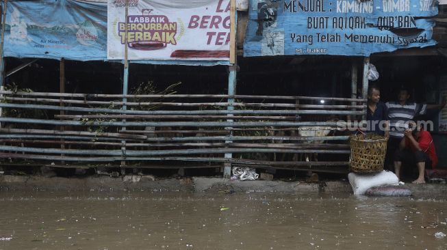 Sejumlah warga berada di salah satu lapak penjual kambing saat banjir merendam kawasan Kemang Utara, Jakarta, Kamis (18/2/2021). [Suara.com/Angga Budhiyanto]