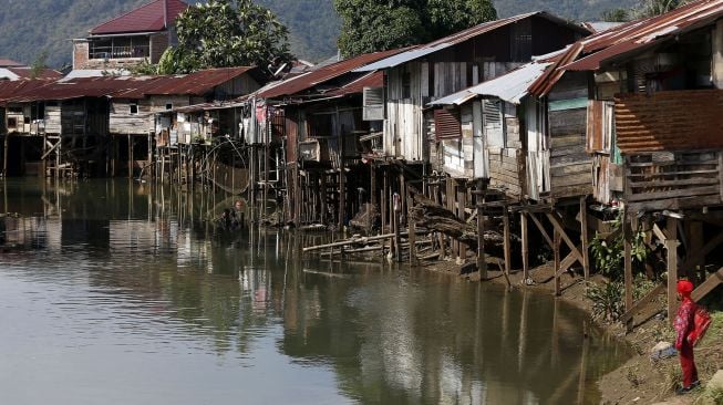 Seorang pelajar berada di kawasan perumahan kumuh yang tidak layak huni di pinggiran Krueng (sungai) Daroy, Aceh Besar, Aceh, Kamis (18/2/2021).  ANTARA FOTO / Irwansyah Putra