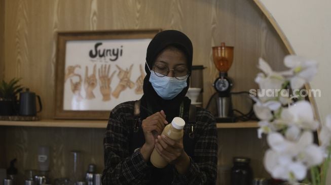 Barista yang seorang tunarungu menyiapkan kopi pesanan pengunjung di Kafe Sunyi, Cilandak, Jakarta Selatan, Kamis (18/2/2021). [Suara.com/Angga Budhiyanto]